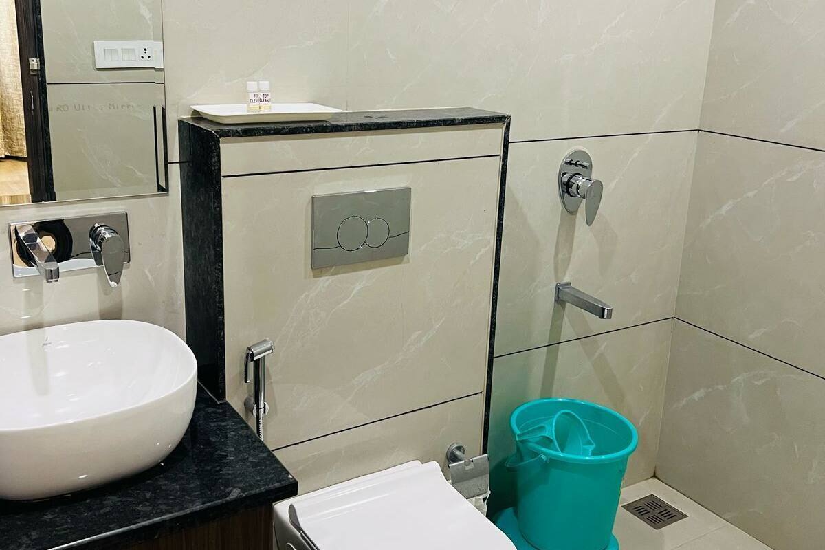 Un baño moderno con un lavamanos, inodoro y bidé blancos, un espejo y un cubo color turquesa.