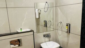 Une salle de bain moderne avec des toilettes blanches, un lavabo et une douche.