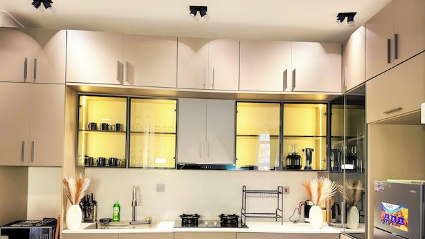 Eine moderne Küche mit hellen Schränken, einer eingebauten Mikrowelle und einem Kühlschrank.