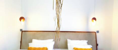 A hotel room with a large bed, two bedside tables, and a hanging plant.