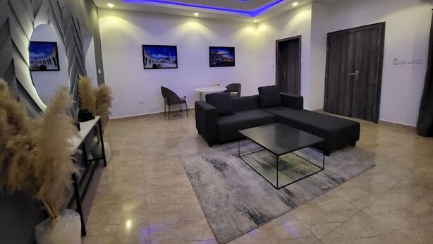 A modern living room with a sectional sofa, a glass coffee table, and a dining area with a small table and chairs.