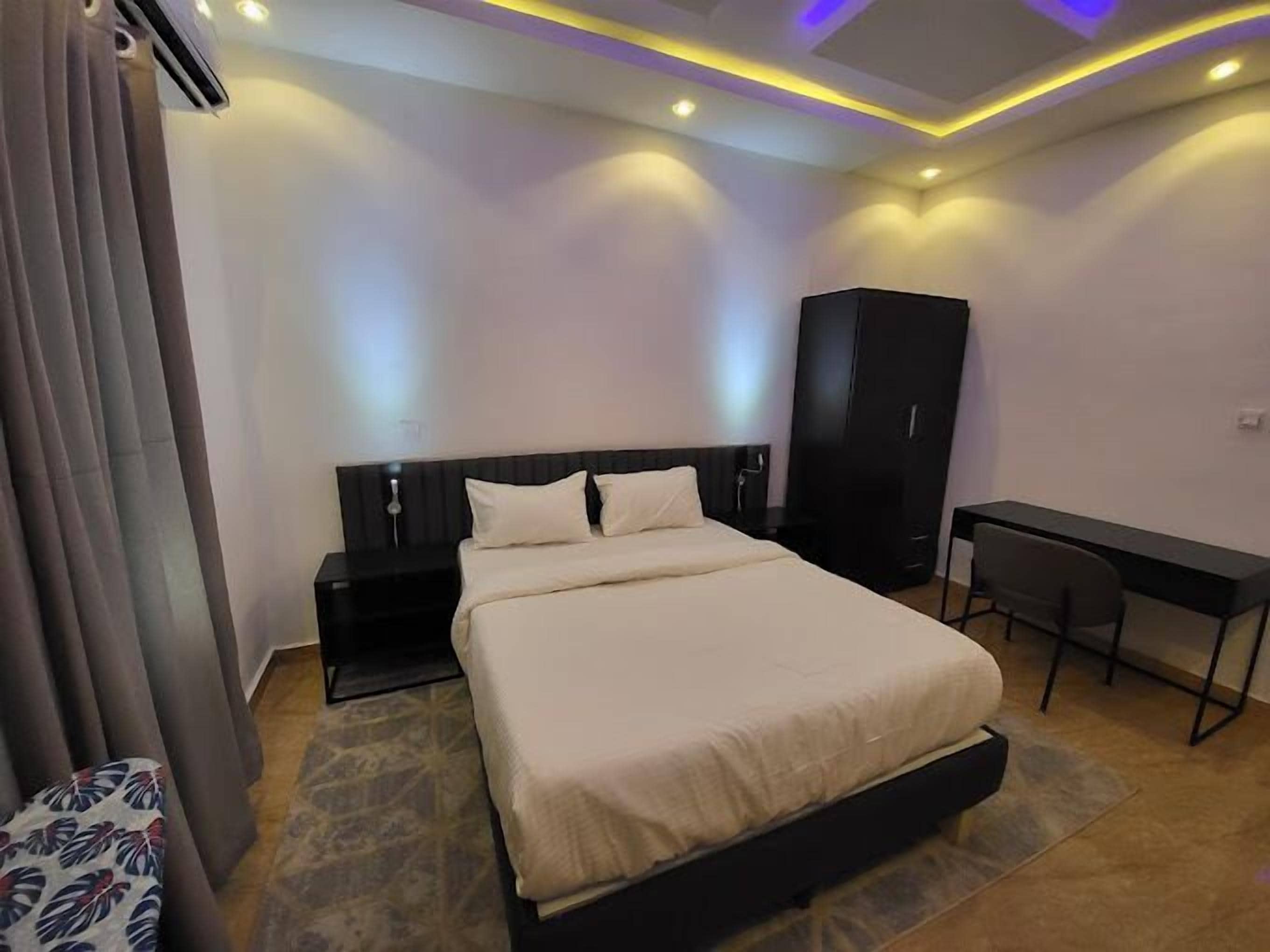 Een moderne hotelkamer met een groot bed, een bureau en een garderobe.