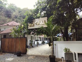 Un patio con piso de baldosas, plantas en macetas y un edificio con un letrero que dice "KALL".