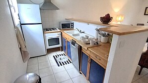 Cozinha compacta com geladeira, micro-ondas, fogão, forno e pia.