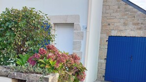 Um edifício com fachada de pedra, porta azul e pequena janela com persianas azuis.