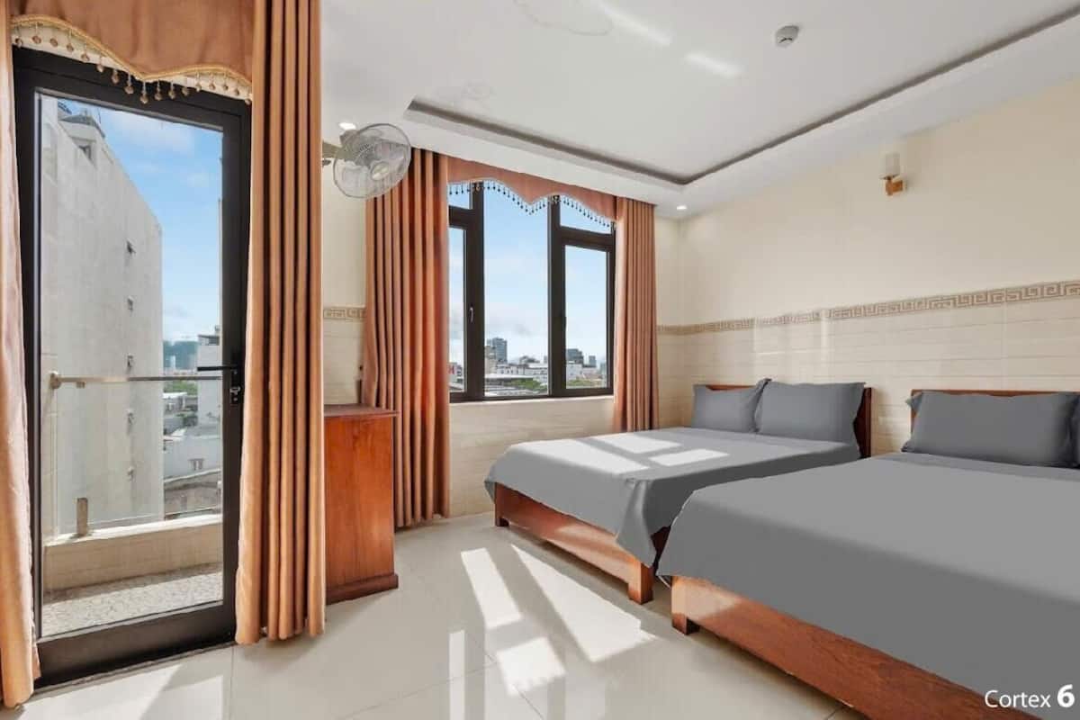 Una camera d'albergo con due letti, un balcone e vista sulla città.