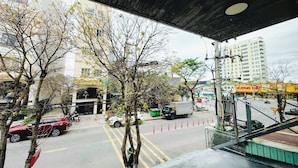 A view from an elevated window overlooking a street with trees, parked cars, and buildings. - BEAR HOTEL & HOMESTAY  (Da Nang)