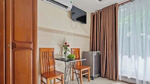 A compact kitchen with a dining table, chairs, a refrigerator, and a TV mounted on the wall. - BEAR HOTEL & HOMESTAY  (Da Nang)