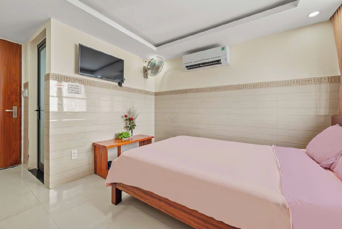 A bedroom with a bed, a TV mounted on the wall, and an air conditioning unit.
