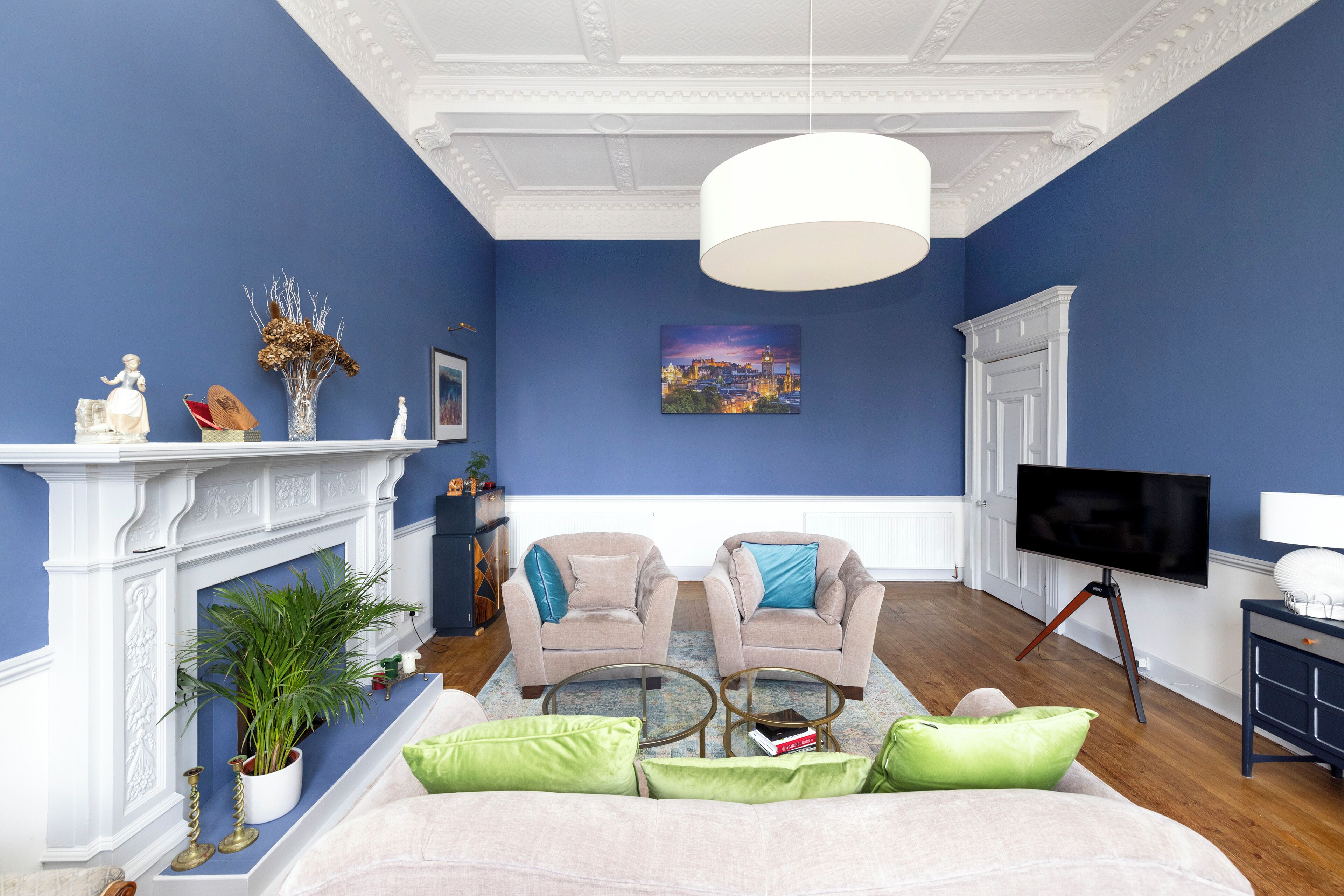 A living room with a fireplace, two armchairs, a sofa, a television, and a painting on the wall.