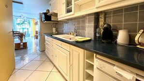 A kitchen with white cabinets, a black countertop, and a dishwasher. There is a window with a view of the outdoors.