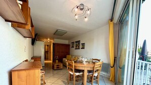 A dining area with a wooden table and chairs, a kitchen in the background, and a sliding glass door leading to an outdoor area.