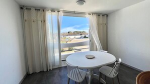 Ein Balkon mit rundem Tisch und Stühlen, Blick auf einen Parkplatz, und ein Gebäude im Hintergrund.