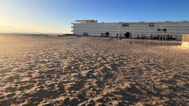 Ein Strand mit einem weißen Gebäude im Hintergrund.