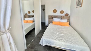 Ein Schlafzimmer mit zwei Betten, einem großen Spiegel und einer Deckenleuchte.