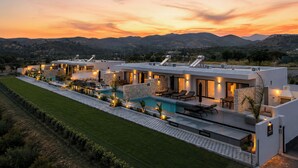 A modern house with a swimming pool, outdoor seating, and a view of mountains.