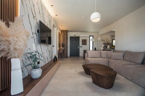 A modern living room with a sofa, coffee table, and a TV mounted on the wall.