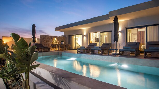 A modern pool area with lounge chairs and a stone wall.