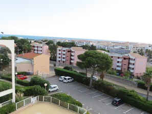 A residential area with apartment buildings, a parking lot, and a view of the sea.