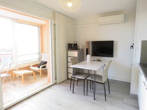 A modern, well-lit room with a dining area, a television, and a coffee maker.