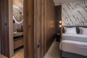 A modern bedroom with a wooden panel wall, a marble-patterned wall, and a bed with white bedding.