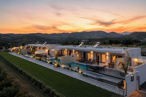 Ein modernes Haus mit Swimmingpool, Sitzgelegenheit im Freien und Blick auf die Berge.