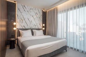 Ein modernes Hotelzimmer mit einem großen Bett, Marmorwand und Blick durch transparente Vorhänge.