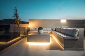 A modern outdoor seating area with a sofa, a small table, and a potted plant.