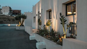 A modern building with a flat roof, rectangular windows, and a concrete planter with plants.