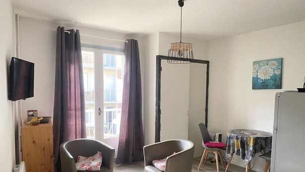 A modern living room with a sofa, chairs, a small table, and a TV.