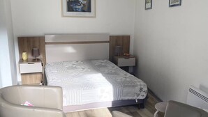 A hotel room with a bed, two bedside tables, a chair, and a small table.