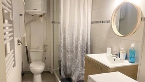 A compact bathroom with a toilet, shower, and sink.