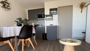 Una cocina moderna con gabinetes grises, un microondas y un pequeño comedor con mesa y sillas.