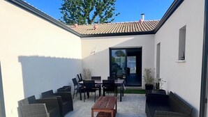 Un patio con mobiliario exterior, una mesa y sillas.