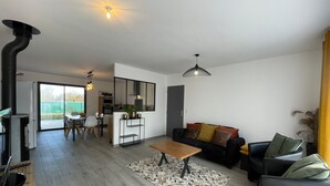 Una sala de estar moderna con un sofá negro, una mesa de centro de madera y un comedor con mesa y sillas.