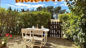 Un patio con una mesa y sillas, un toldo a rayas y una valla de madera.