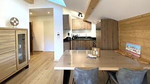 Eine moderne Küche mit Holzausstattung, einem Esstisch mit Stühlen und Blick in den angrenzenden Wohnbereich.