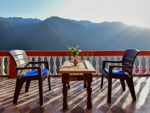 A balcony with two chairs, a table, and a vase of flowers.