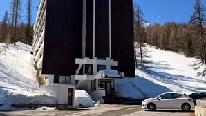 A modern building with a large dark facade, a white entrance, and a car parked in front. - Charming renovated studio in the mountains, pets allowed (Vars)