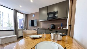 A modern kitchen with a wooden table set for two, a microwave, and a coffee maker. - Charming renovated studio in the mountains, pets allowed (Vars)
