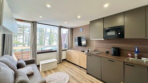 A modern kitchen with a microwave, oven, and sink. There is a dining table and a sofa in the living area. - Charming renovated studio in the mountains, pets allowed (Vars)