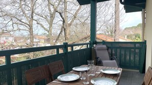 A wooden deck with a table set for two, overlooking a residential area.