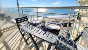 Ein Balkon mit Tisch für zwei Personen, mit Blick auf einen Strand.