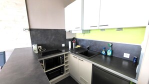 Eine kleine Küche mit weißen Schränken, einer schwarzen Arbeitsplatte und einem eingebauten Backofen.