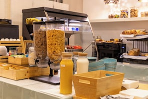 A breakfast buffet with various food items, including cereal, milk, and pastries.