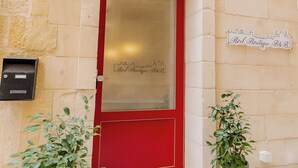 Una puerta roja con un panel de vidrio, dos macetas y un letrero que dice 