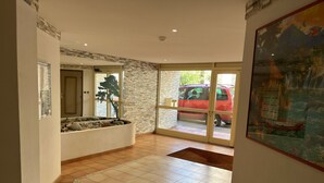 A spacious lobby with a tiled floor, a stone accent wall, and a large glass door leading outside.