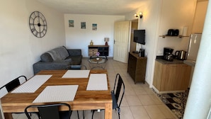 A compact living space with a dining area, kitchenette, and a sofa.