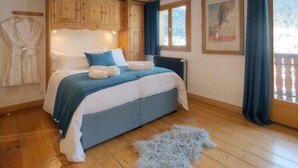 A bedroom with a bed, wooden cabinets, a radiator, a framed picture, and a window with curtains. - 5☆ Chalet, 15 ppl, spa, pet-friendly, La Clusaz (La Clusaz)