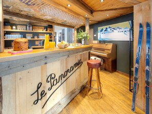 A wooden bar area with a piano, bar stools, and skis on display.
